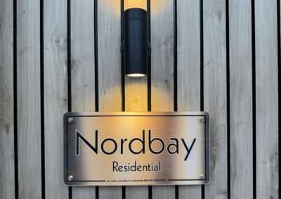 Nordbay chalet met grote ramen, lessenaarsdak en speelse gevelafwerking — moderne vakantiewoning met luxe interieur en veel lichtinval.